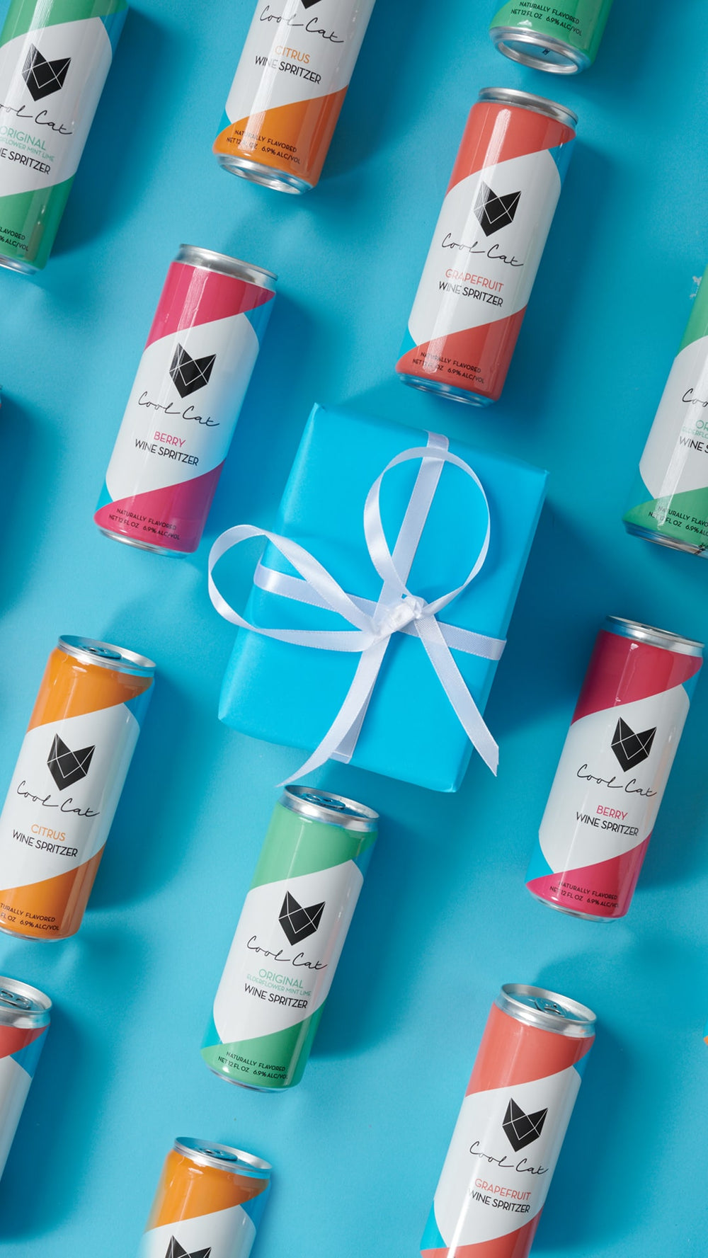 Every flavor of Cool Cat Sparkling Cocktail surrounding a holiday present.