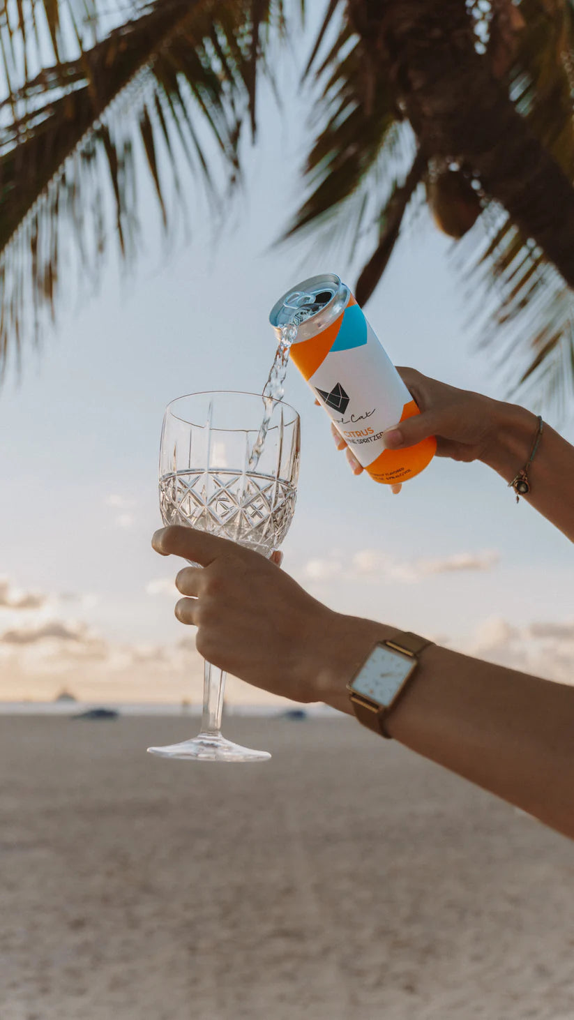 A Cool Cat Citrus Sparkling Cocktail being poured into a wine glass.