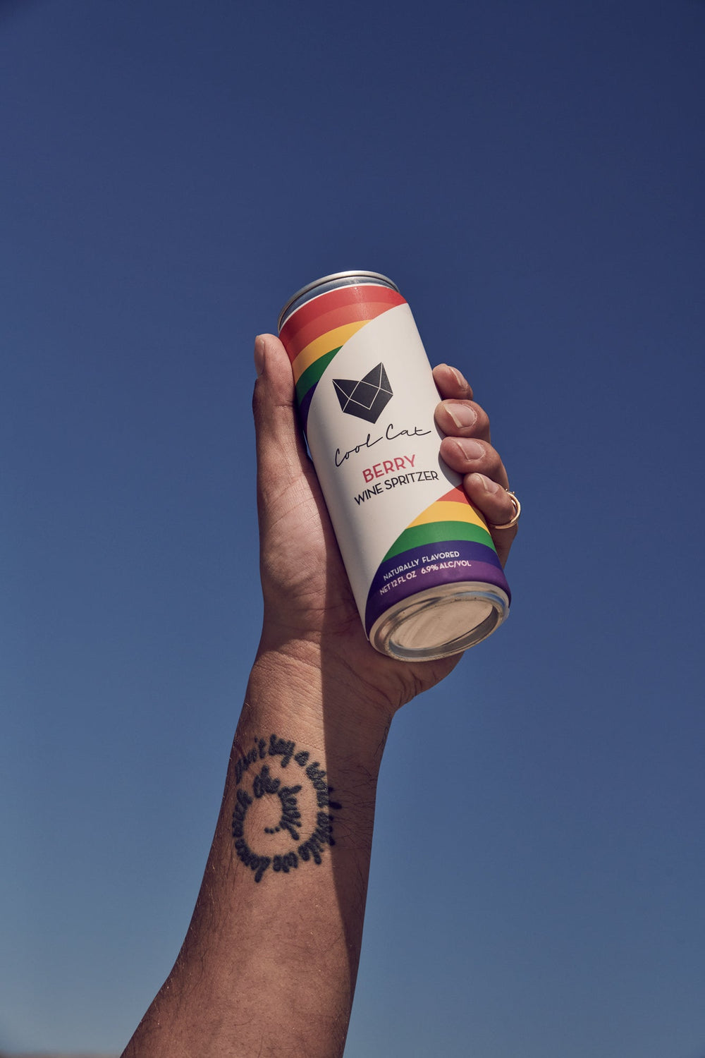 A hand holds up a limited-edition Pride can of Cool Cat to the sky.