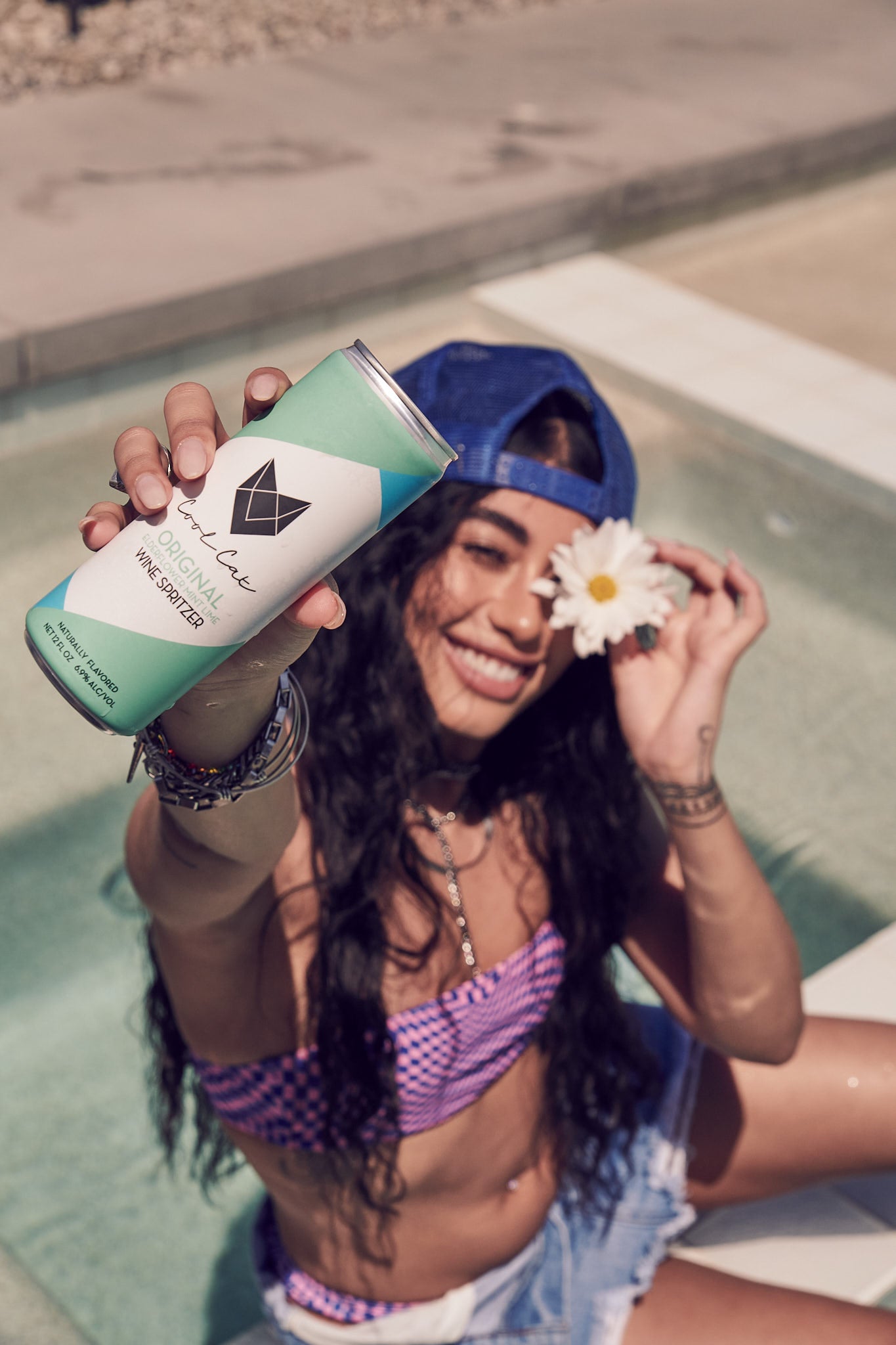 Camila Romero holds a Cool Cat Wine Spritzer and a daisy by the pool.