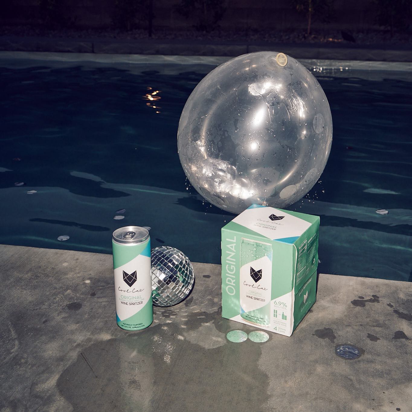 Original flavor can of Cool Cat Wine Spritzer next to a 4-pack at a disco pool party.