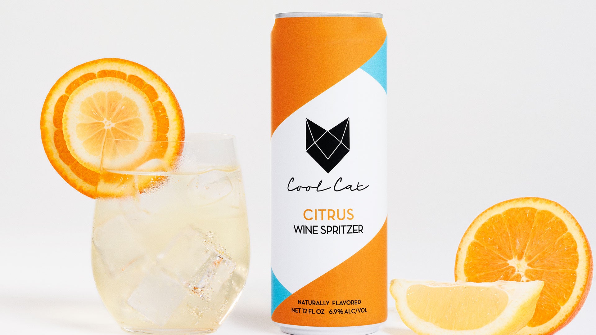 Cool Cat Citrus Sparkling Cocktail next to a glass garnished with oranges and lemons.
