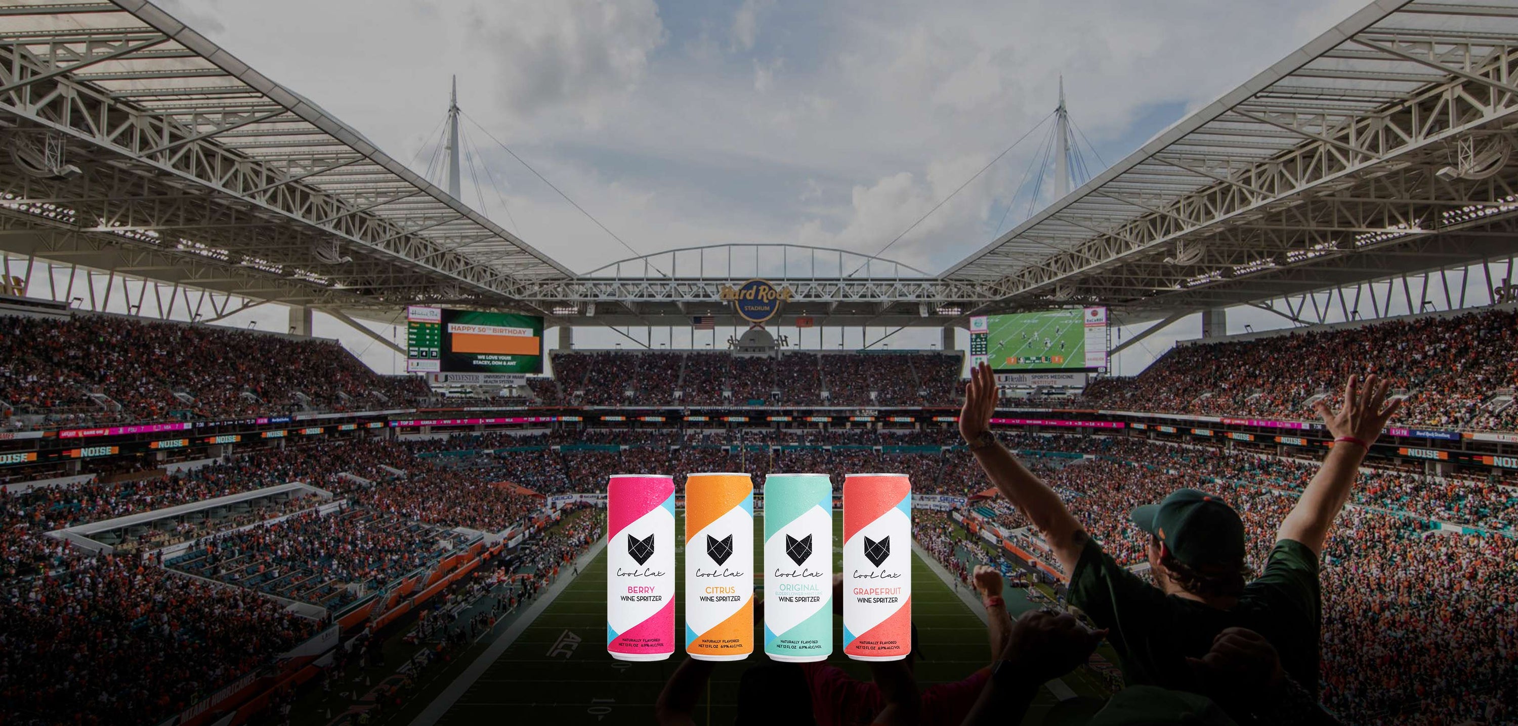 The four flavors of Cool Cat canned wine seltzer in front of the Miami Hurricanes football field.