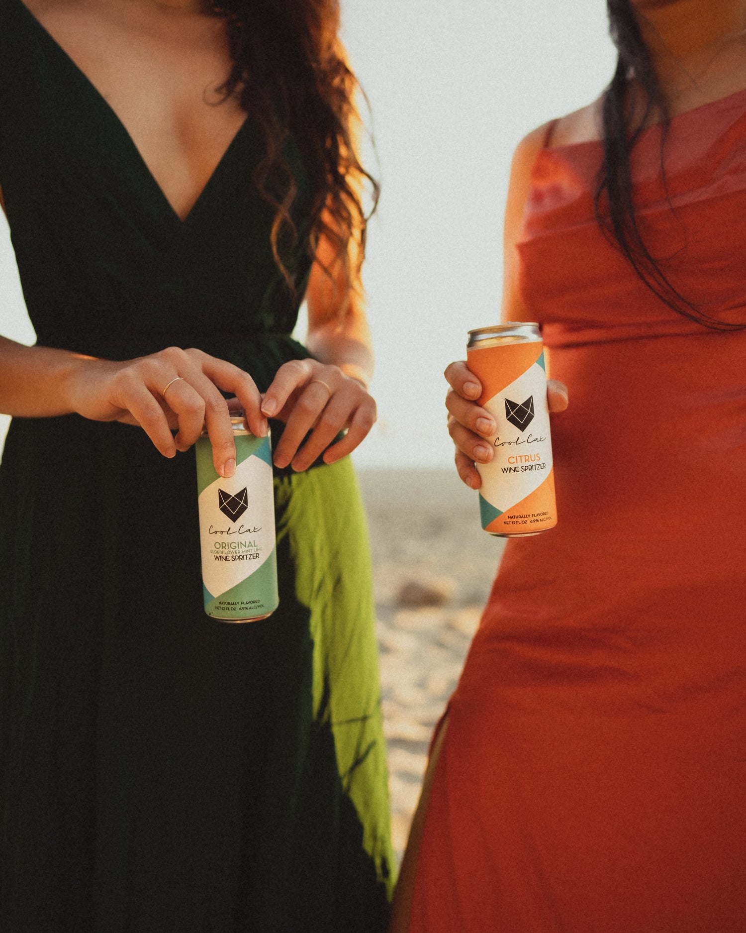 Two women stand on the beach with Cool Cat Sparkling Cocktails.