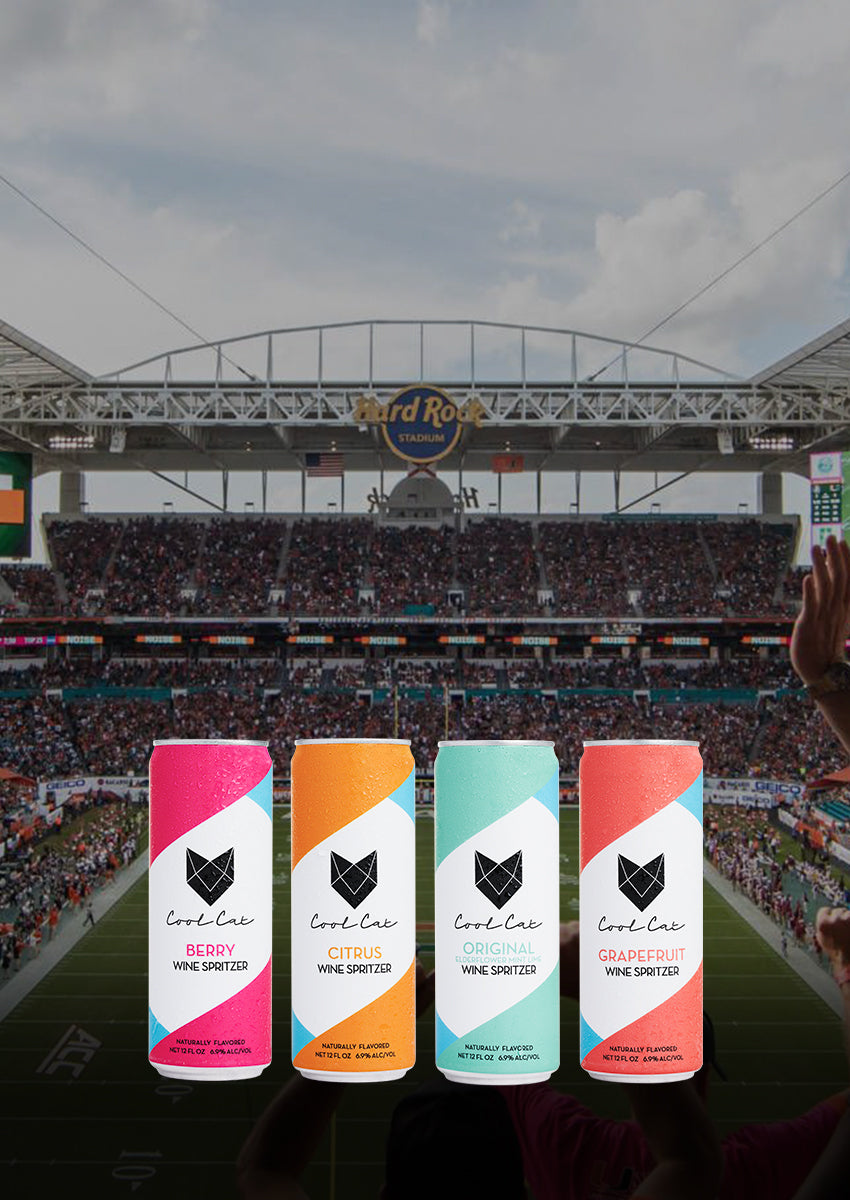 The four flavors of Cool Cat canned wine seltzer in front of the Miami Hurricanes football field.