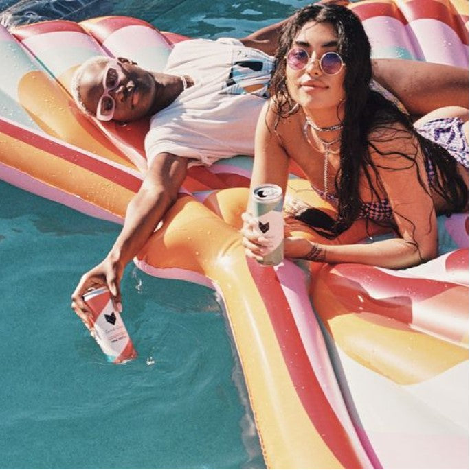 Two young women in a pool holding Cool Cat Wine Spritzers.