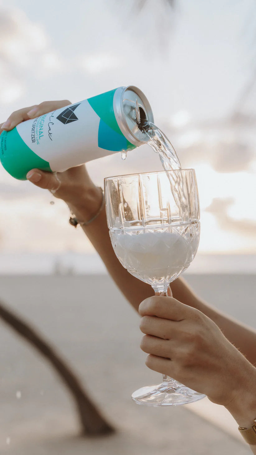 Someone pours a can of Cool Cat Elderflower Sparkling Cocktail into a wine glass.