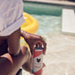 Someone holds a can of Cool Cat Grapefruit Sparkling Cocktail by the pool.